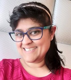 A person wearing glasses and a pink shirtDescription automatically generated